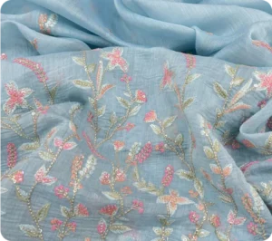 "Light blue Chanderi fabric with delicate floral embroidery in pastel pink, peach, and gold threads"