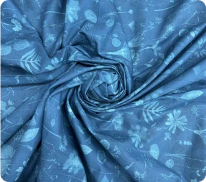 "Blue cotton-linen blend fabric with subtle floral and leaf pattern, arranged in a spiral fold"